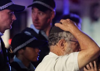 A member of the Jewish community reacts next to Australian law enforcement officers at the scene of the Bondi Beach shooting in Sydney on Dec. 14, 2025.