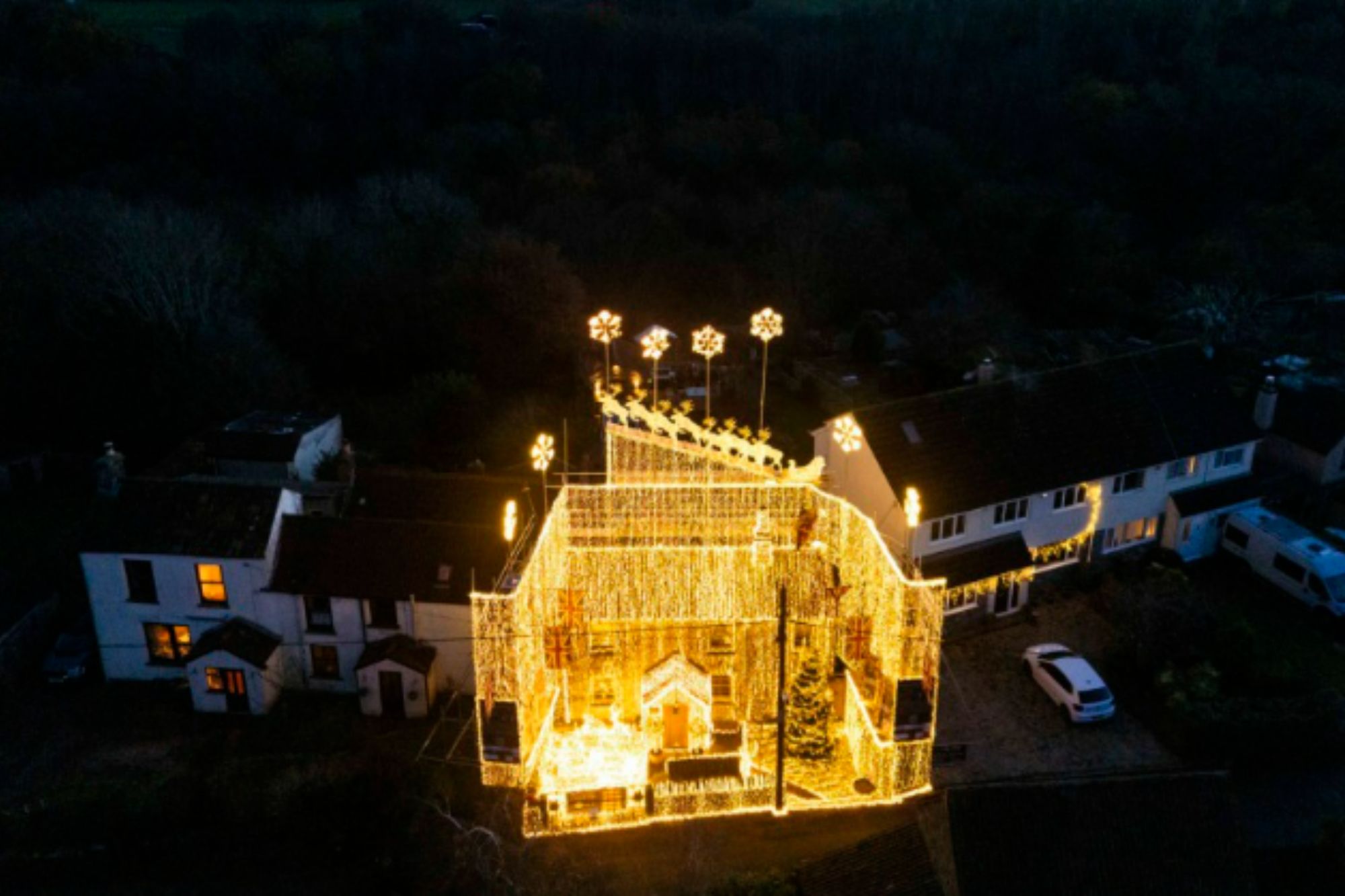 An image collage containing 1 images, Image 1 shows House brightly illuminated with Christmas lights at night, featuring a Santa and reindeer display on the roof