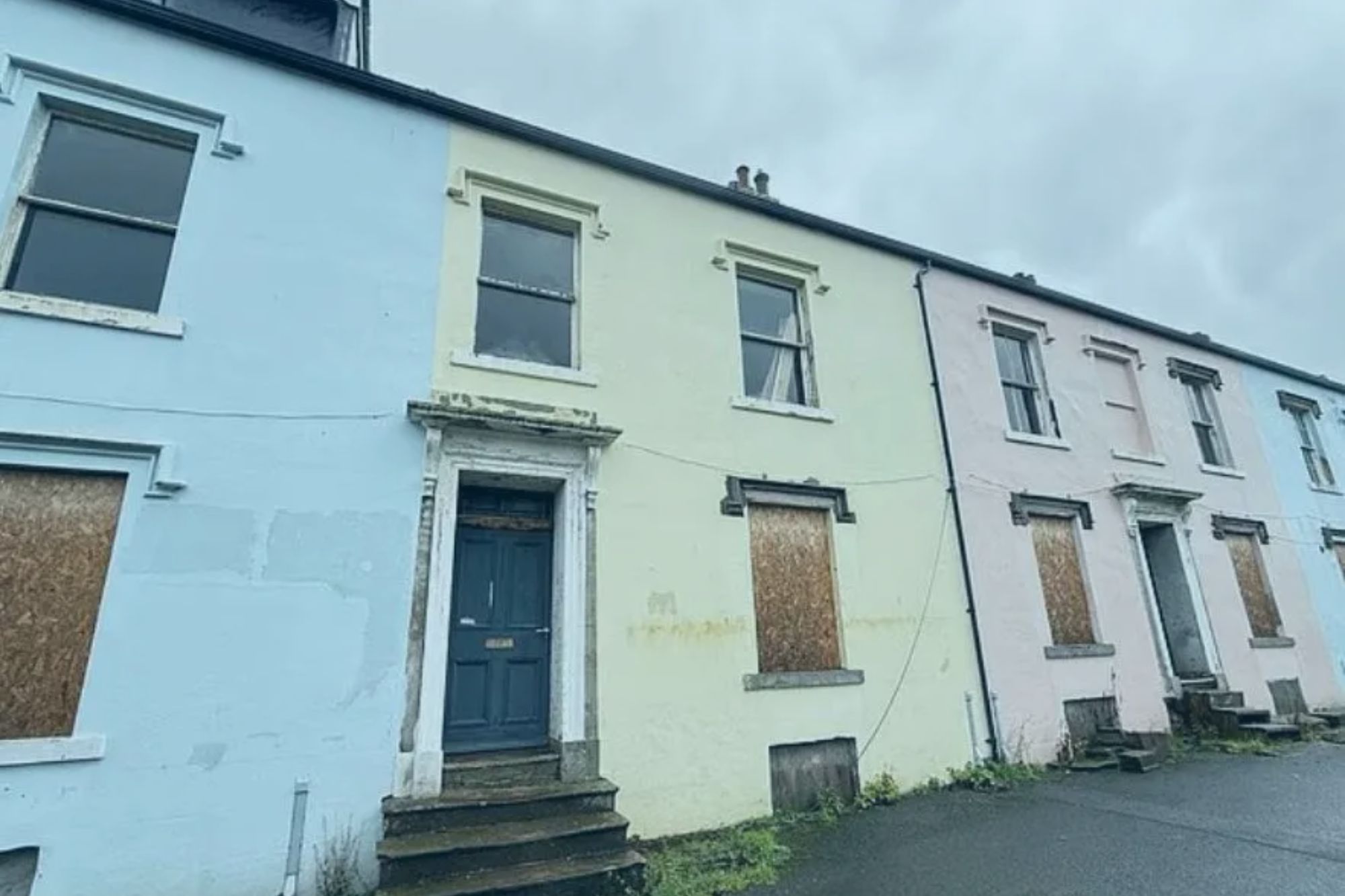 An image collage containing 1 images, Image 1 shows A row of dilapidated Victorian houses in pastel colors with boarded-up windows