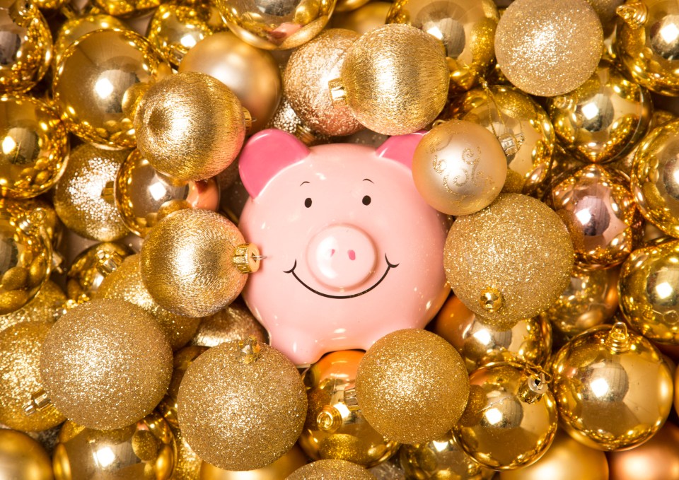 Pink piggy bank surrounded by golden Christmas ornaments.