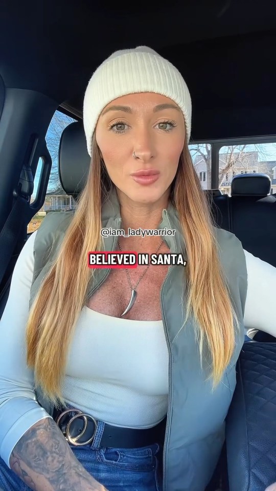 Carla Dillon in a car, wearing a white beanie and olive vest, with text "@iam_ladywarrior BELIEVED IN SANTA," on the image.