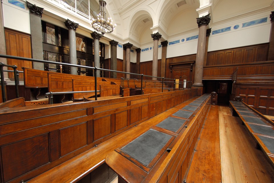 Interior view of St. George's Hall in Liverpool, showing tiered wooden benches and polished columns.