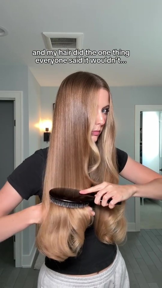 A woman brushing her long, wavy blonde hair.