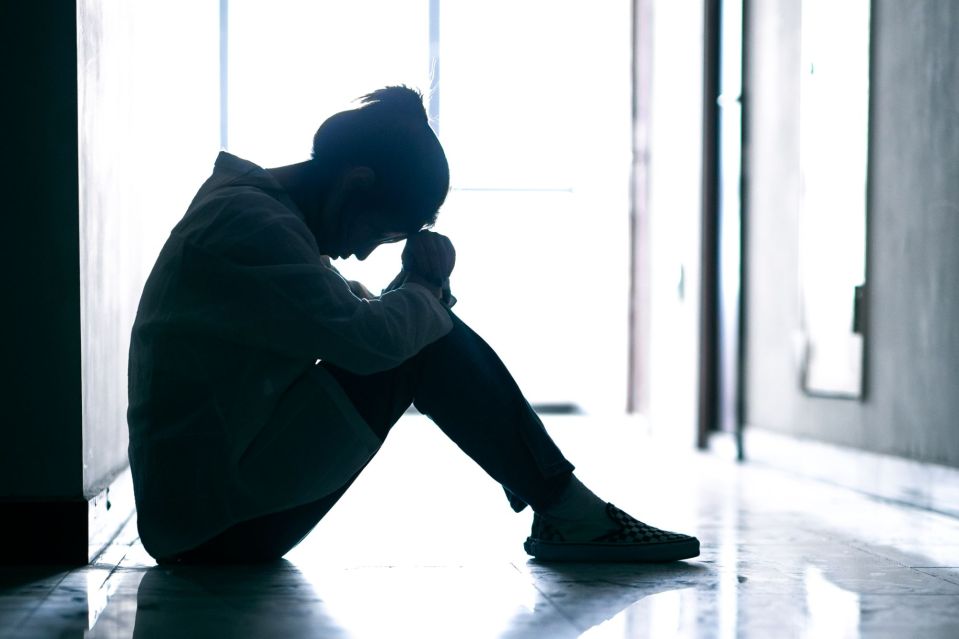 An image collage containing 1 images, Image 1 shows A young woman sits curled up on the floor of a corridor, appearing distressed