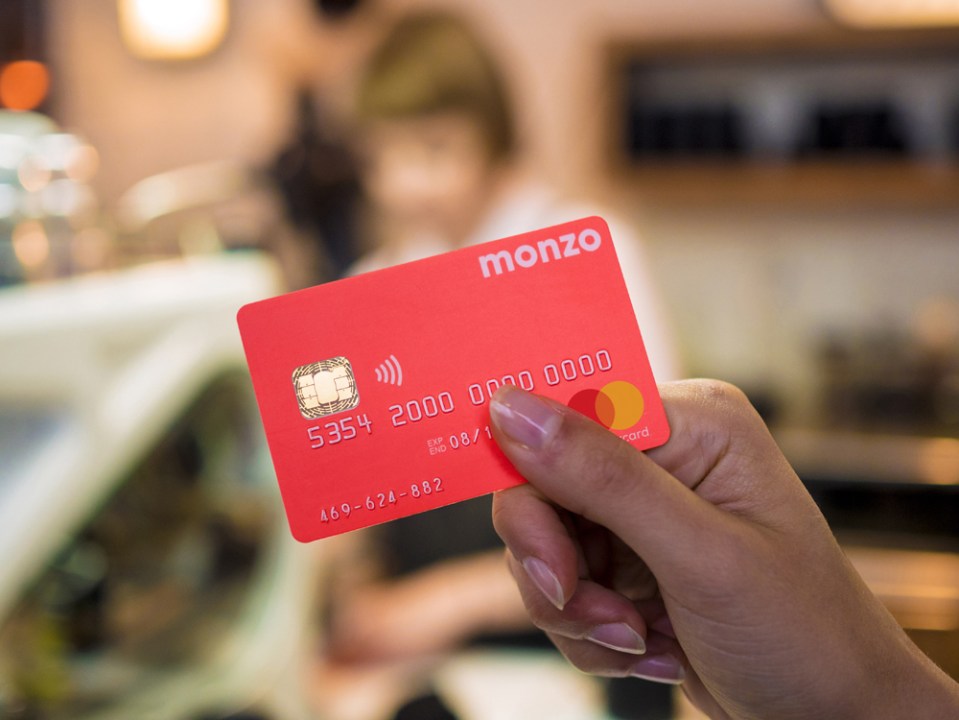 A hand holding a Monzo bank card.