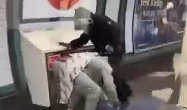 One of the men is on the ground while two youths lay into him on the Tube platform at Colliers Wood, south London