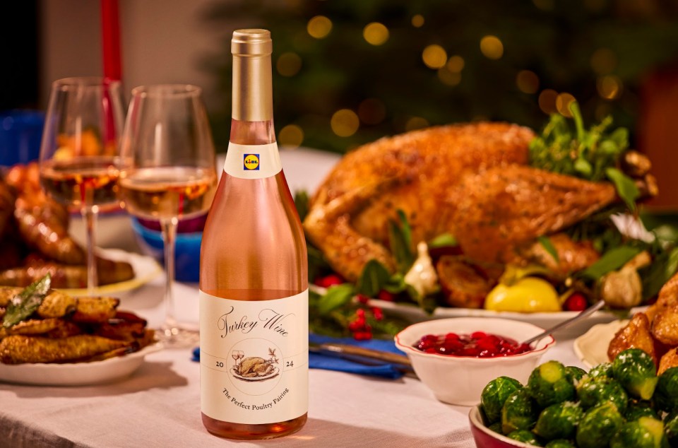 Lidl Turkey Wine bottle with a roasted turkey, brussels sprouts, and cranberry sauce on a Christmas dinner table.