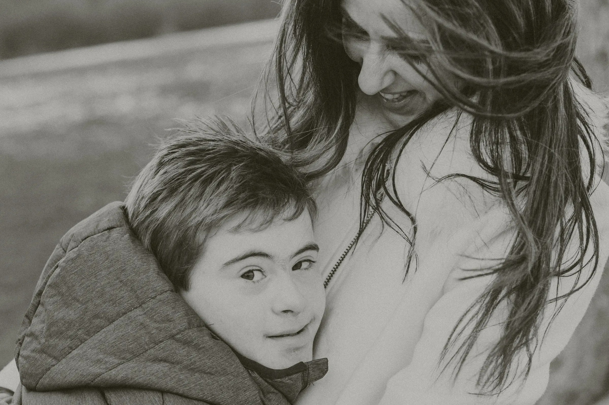 Black and white photo of a woman embracing a boy with Down syndrome.