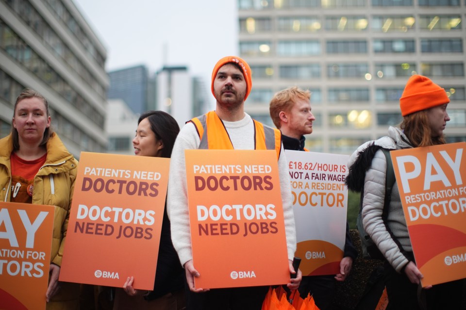 Resident doctors outside St Thomas' Hospital in London holding signs during a strike for better pay.