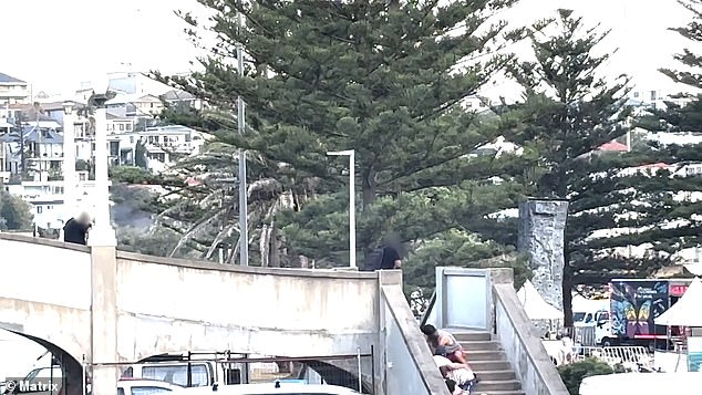 The previously unseen footage from the attack showed two men, a child, a teenage boy, and a woman cowering on a set of steps leading up to a footbridge, where suspected the terrorist shooters allegedly opened fire on people celebrating Hanukkah