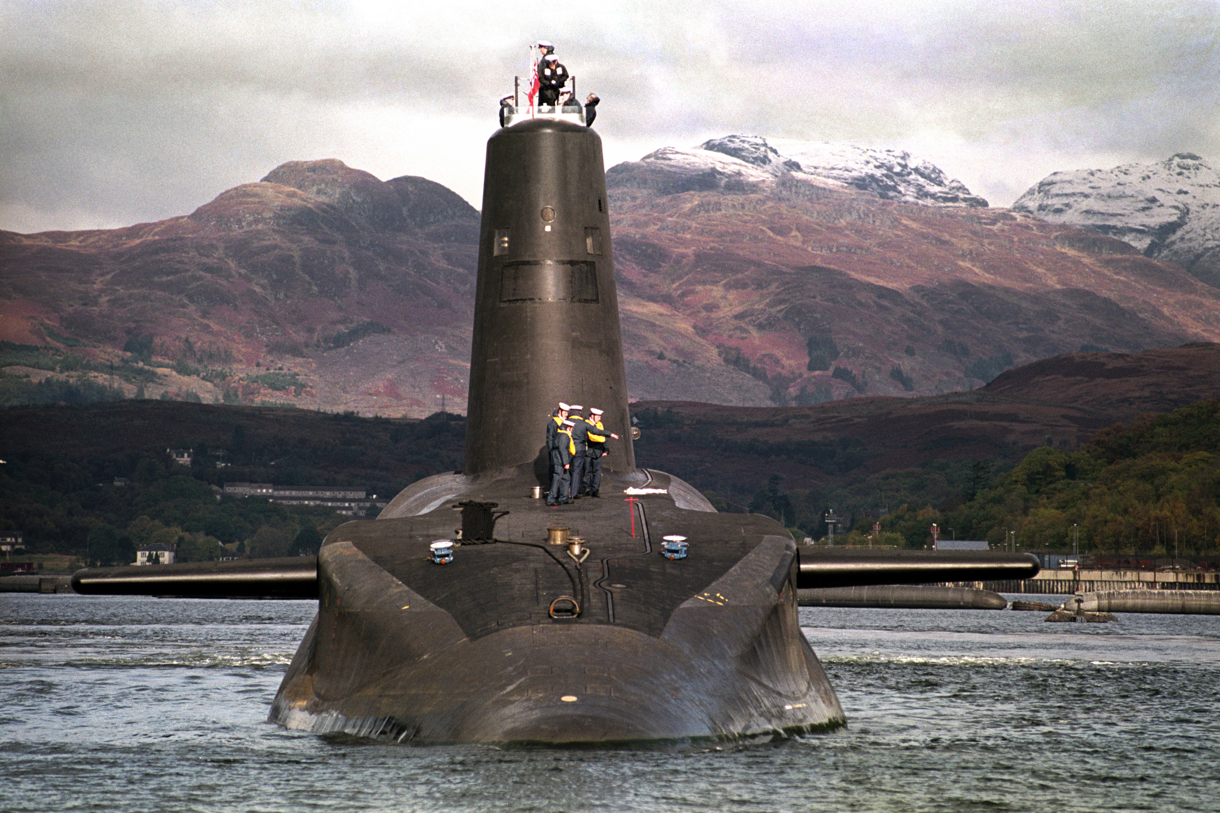 HMS Vanguard, Britain's first Trident nuclear submarine, on the River Clyde, Scotland, with mountains in the background.