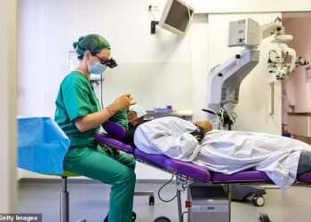 Side view of a doctor examining patient's eye during surgery