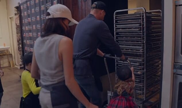 A new glimpse of Archie (left in yellow) and Lilibet (right in tartan) as they push a trolley of food for the poor on Thanksgiving in a Happy Holidays video