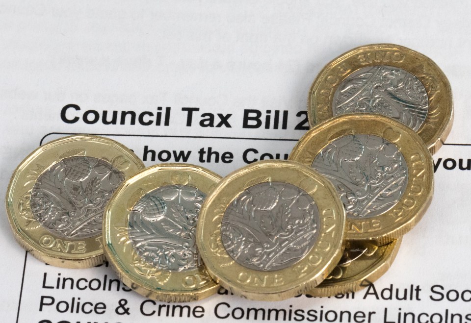 Several new British pound coins resting on a council tax bill.