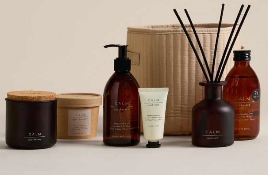 An assortment of "CALM apothecary" products, including a candle, wash, hand cream, and diffuser.