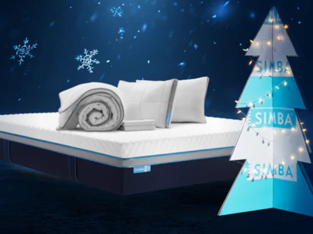 Simba mattress with pillows and rolled duvet, next to a branded Christmas tree with lights.