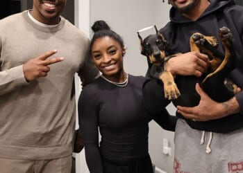 Simone Biles (C) and Jonathan Owens (R) pose with the breeder and their new doberman, which appears to have had its ears chopped in a painful procedure