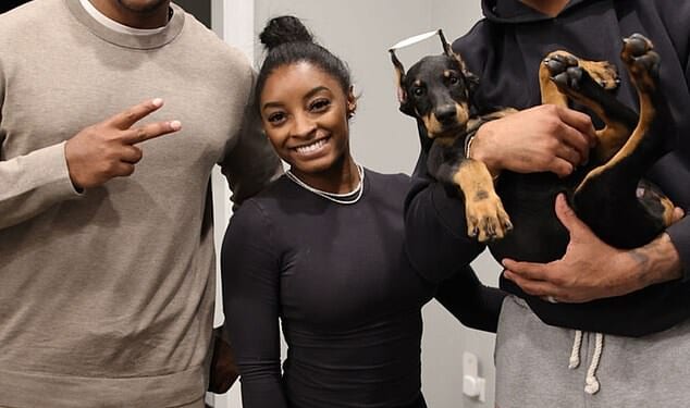 Simone Biles (C) and Jonathan Owens (R) pose with the breeder and their new doberman, which appears to have had its ears chopped in a painful procedure