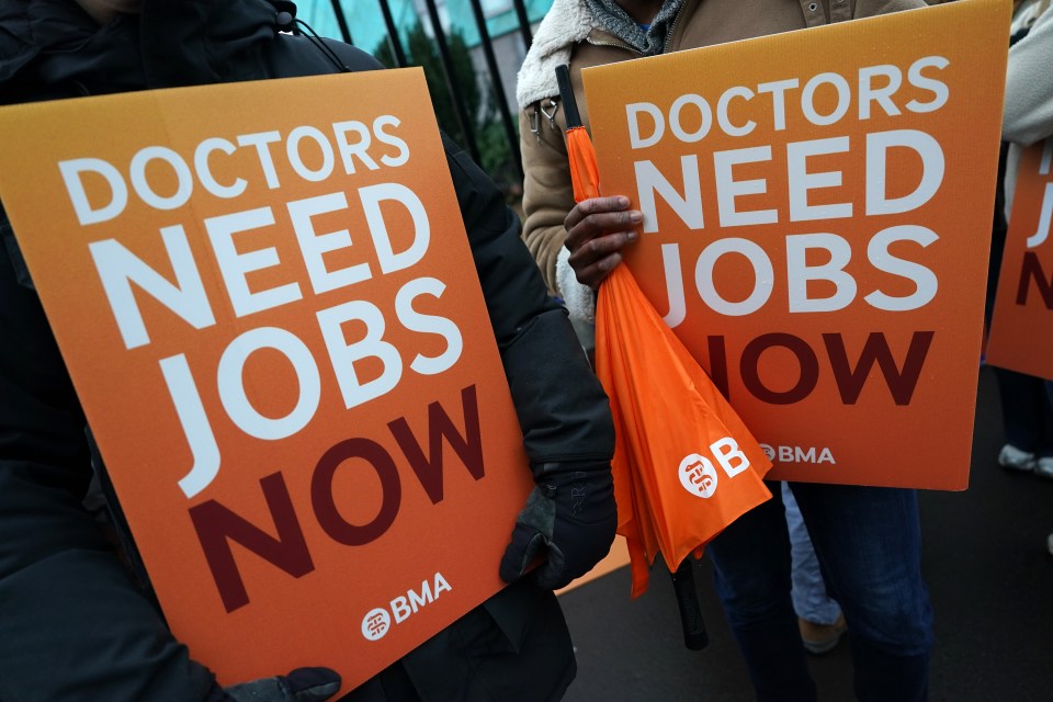 Two people holding orange placards that read "DOCTORS NEED JOBS NOW" with the BMA logo.