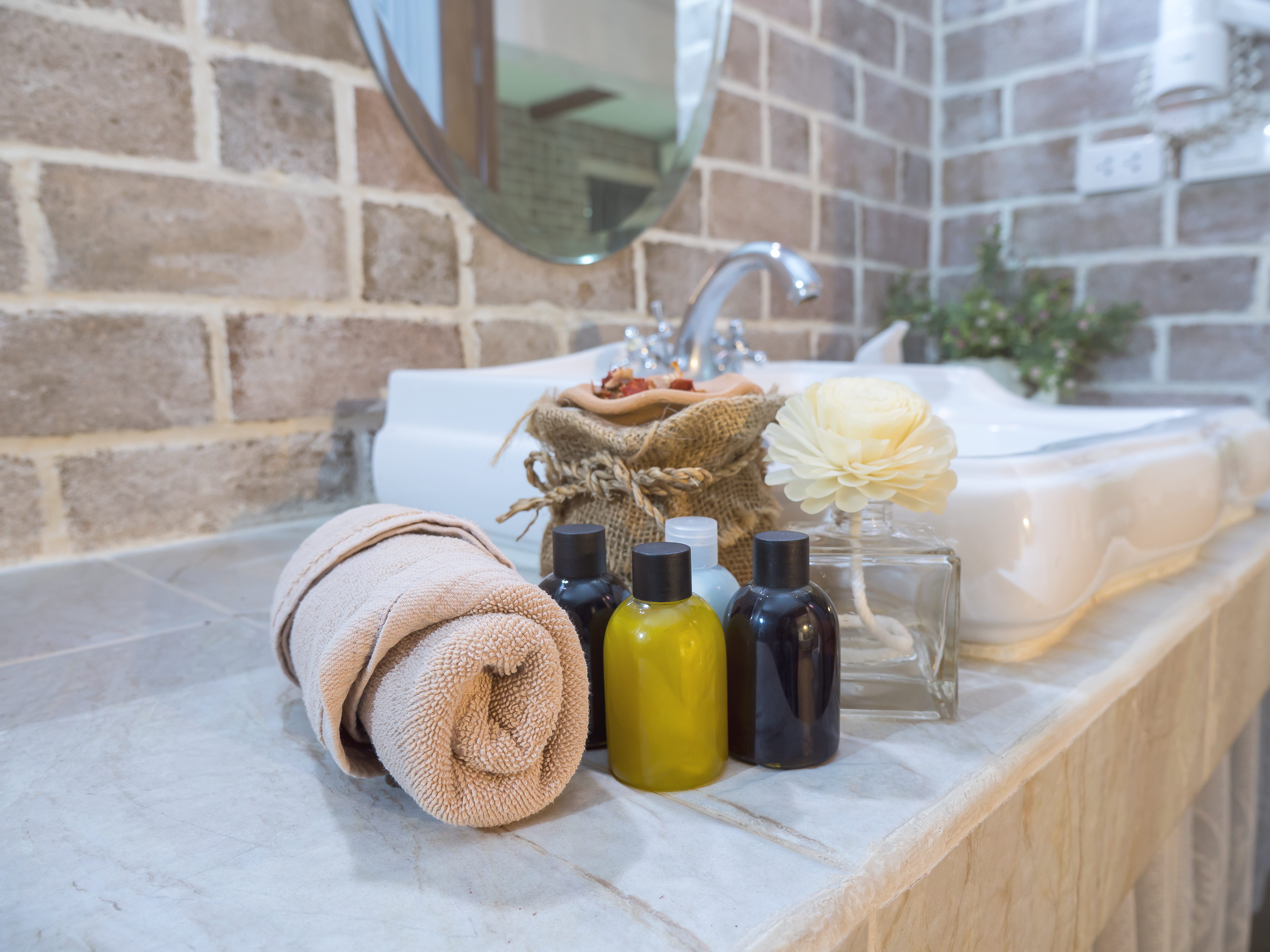 Toiletries and a rolled towel on a bathroom counter.