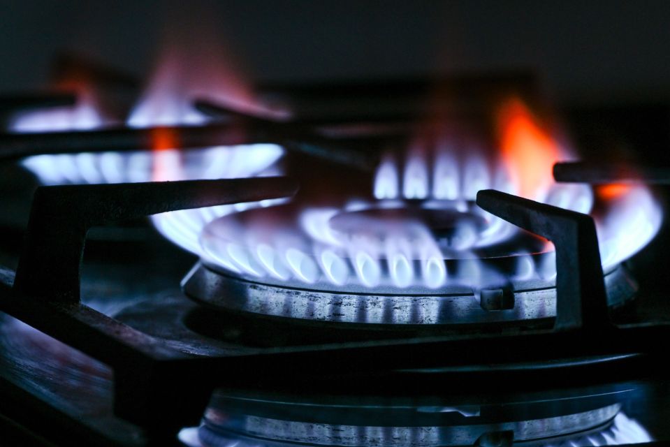 Natural gas burners on a gas stove with blue and orange flames.