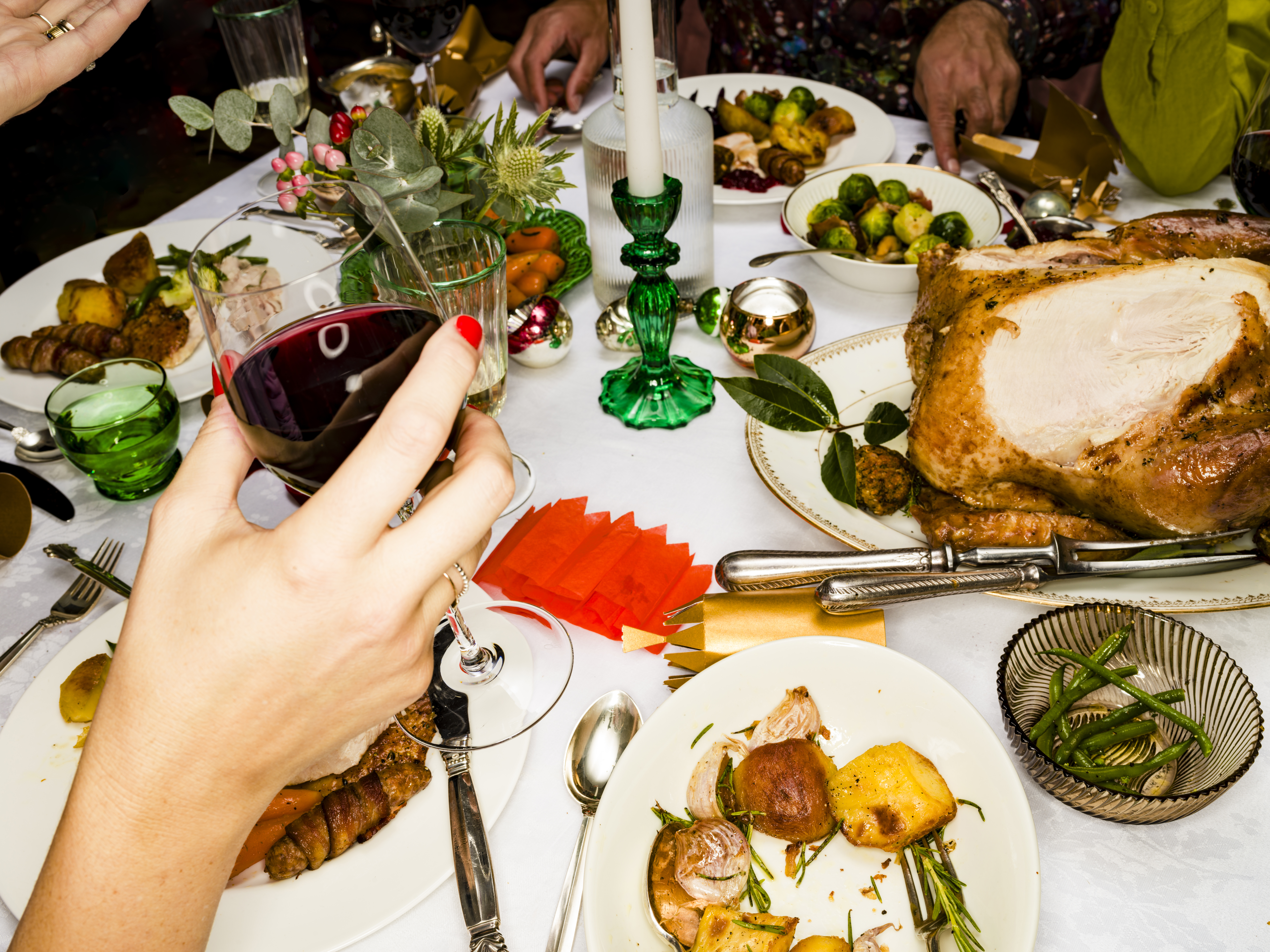 Close Up Woman Drinking Red Wine At Christmas Dinner Table Over Roasted Turkey, Potatoes, And Decorations