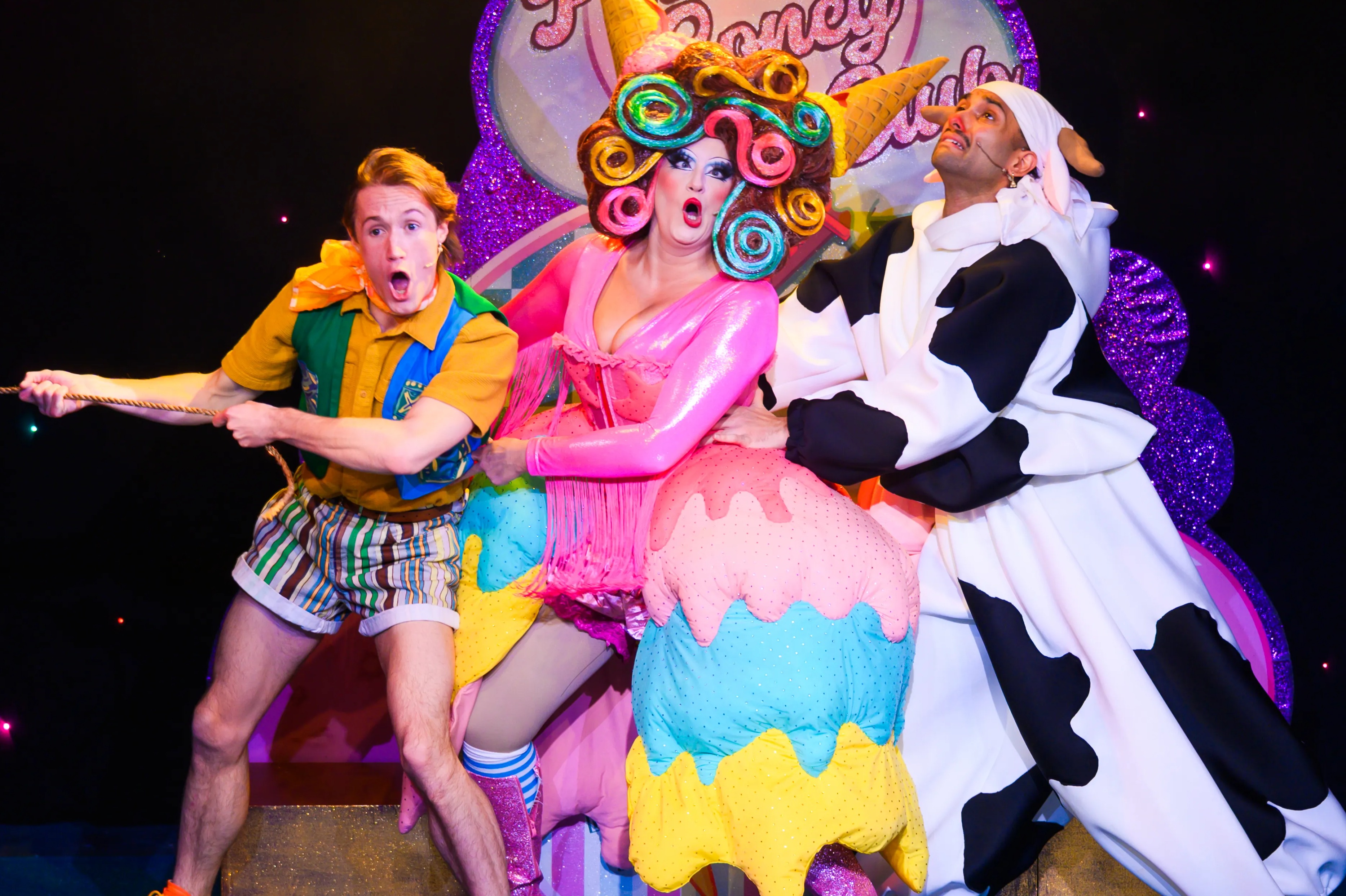 Three performers from a Jack and the Beanstalk production, in colorful costumes, pose on stage.