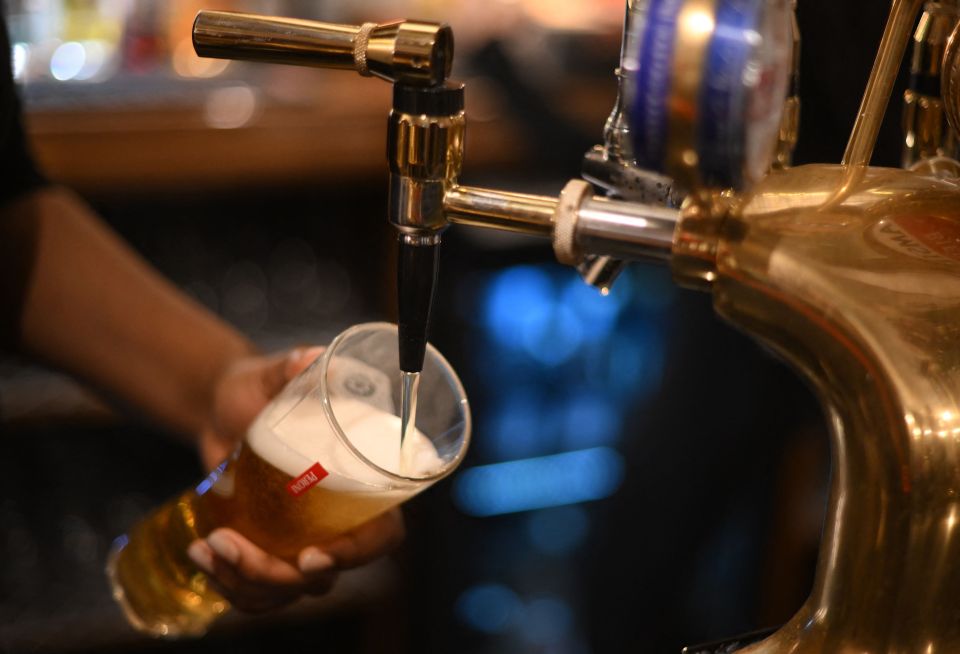 Employee pouring Peroni beer into a glass from a tap at a bar.