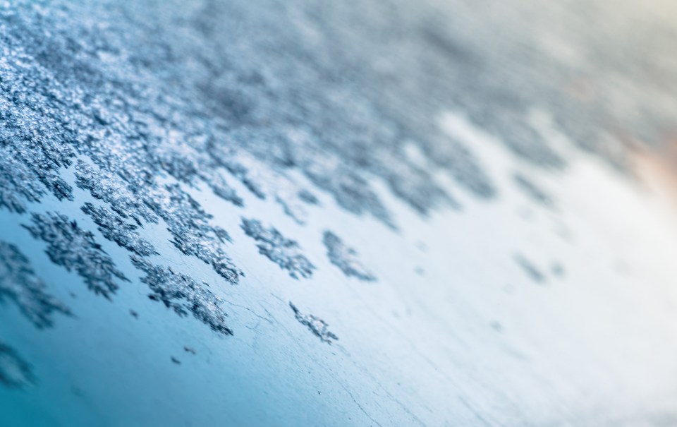 Macro photo of water freezing on a car windshield in the morning, ice textures