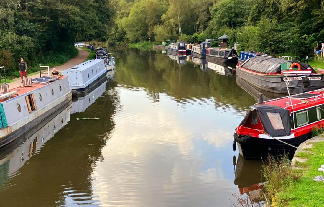 Boats docked on a canal with trees along the banks.