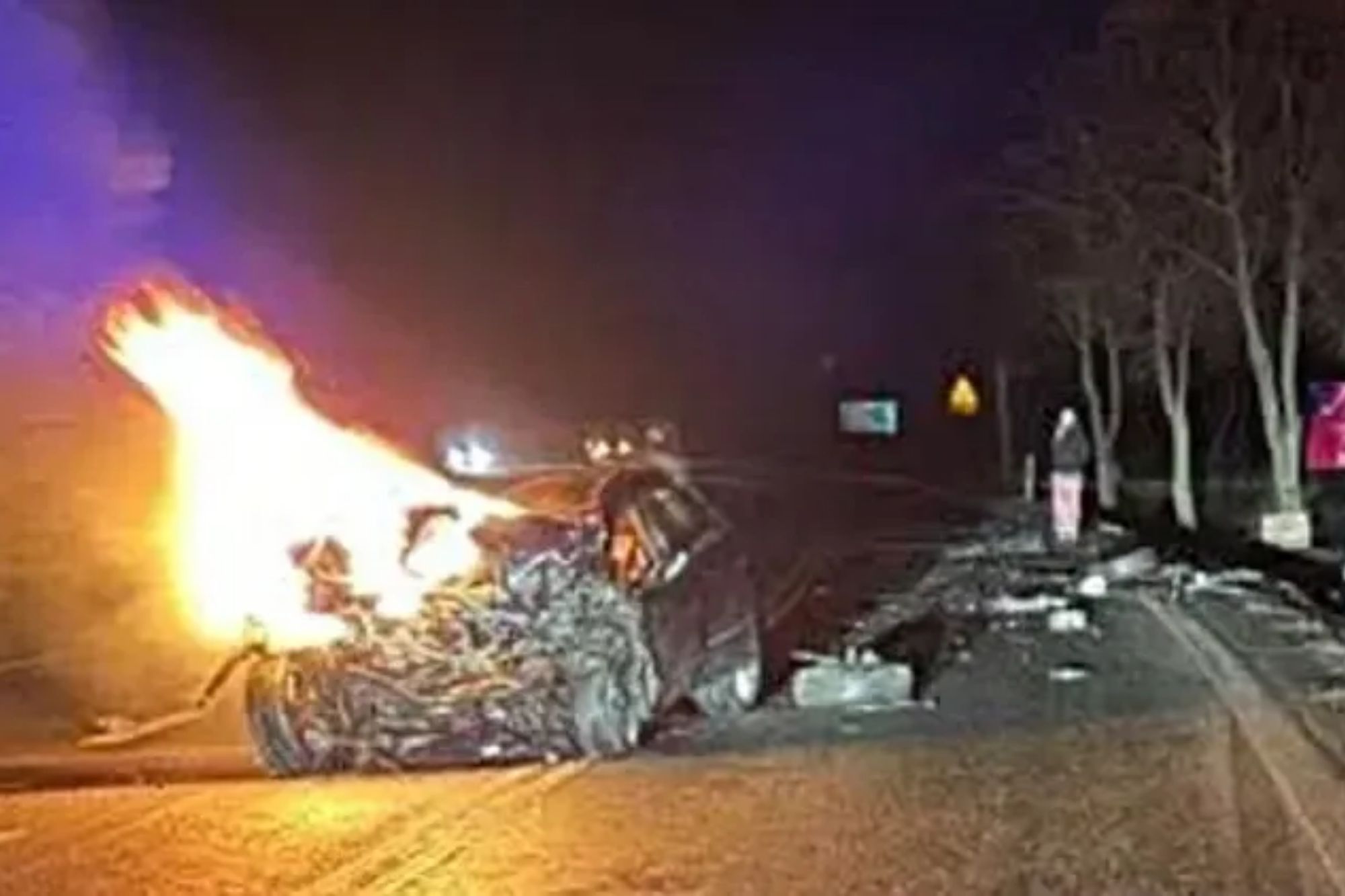 An image collage containing 1 images, Image 1 shows A fiery car crash on a dark road with debris scattered and a person standing nearby