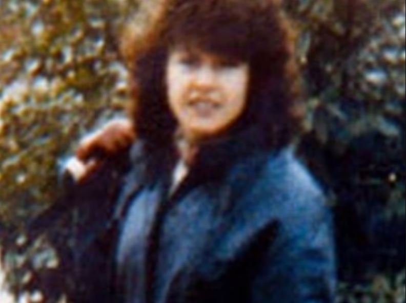 Woman with dark curly hair and a dark jacket.