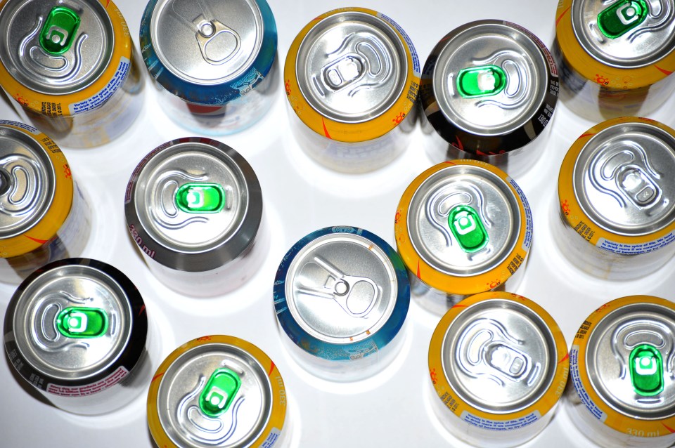 The tops of a variety of cans of fizzy pop photographed against a white background.