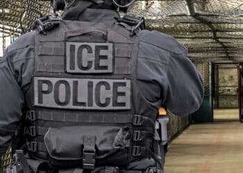 An ICE officer walks down a hall at a detention facility.