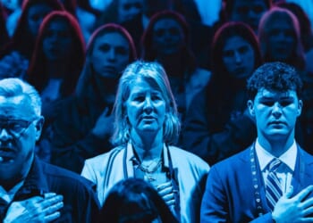 Attendees stand for the National Anthem during Turning Point's annual AmericaFest conference in Phoenix, Arizona, on Dec. 21, 2025.