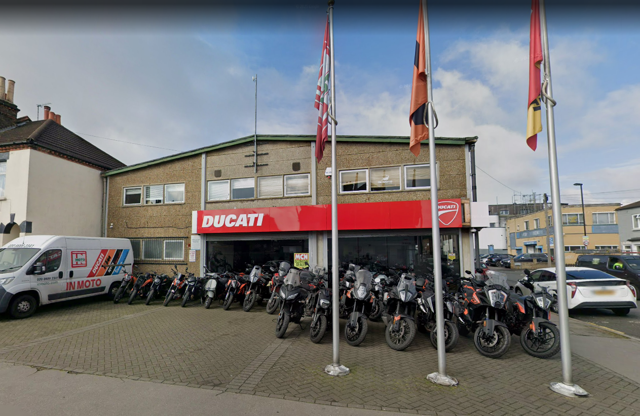 The storefront of Ducati Croydon, with many motorcycles parked outside and a white In Moto van.