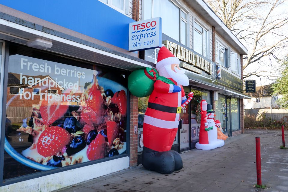 An inflatable Santa and snowman in front of a Tesco Express and an Istanbul Barber shop.