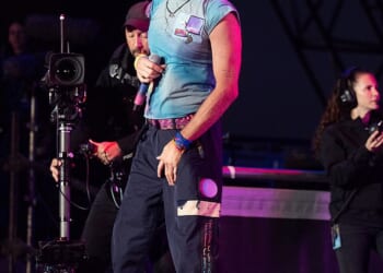 Chris Martin wearing one of his signature tie-dyed t-shirts for his performance at Glastonbury in summer 2024