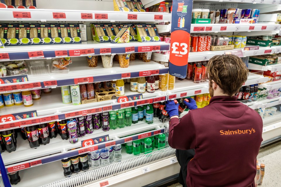 Sainsbury's employee stocking shelves in a supermarket.
