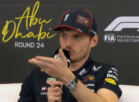 Max Verstappen speaking into a microphone at an event, with text "Abu Dhabi Round 24" in the background.