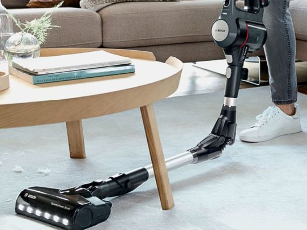Person using a Bosch Athlet vacuum cleaner to clean under a coffee table.