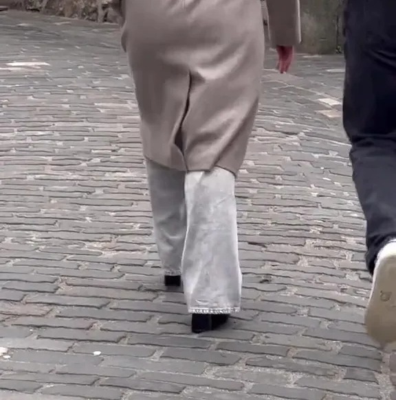 Two people walking away from the camera on a cobblestone path.