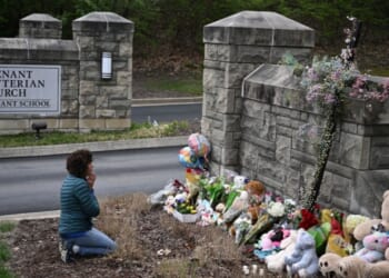 Robin Wolfenden prays at a makeshift memorial for victims outside the Covenant School building at the Covenant Presbyterian Church following a shooting in Nashville, Tennessee, on March 28, 2023.