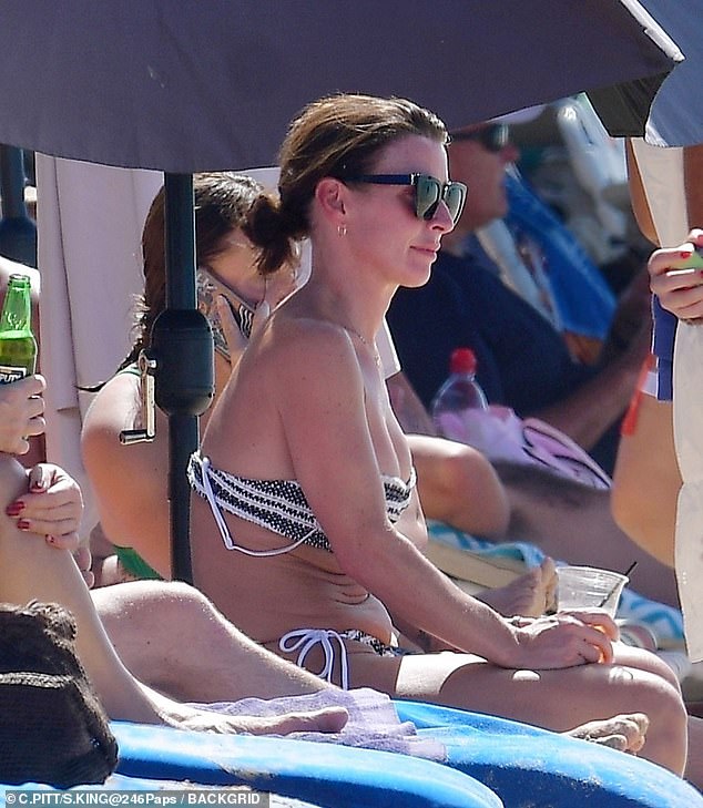 She enjoyed a drink while watching her sons have fun in the sea