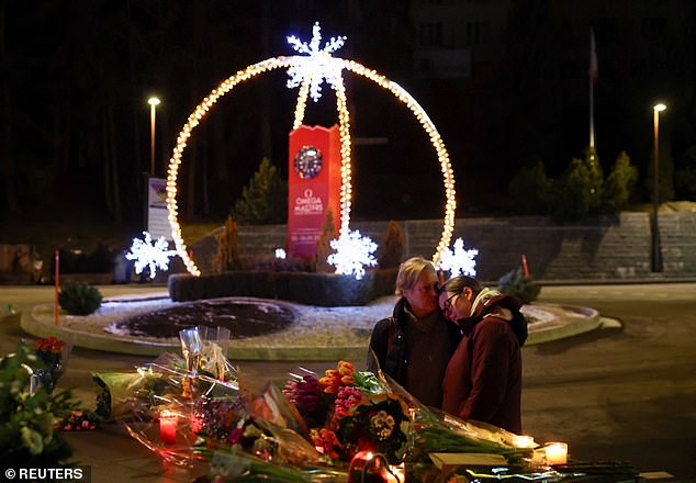 A pair of people embrace near the site of the bar on January 1, 2026