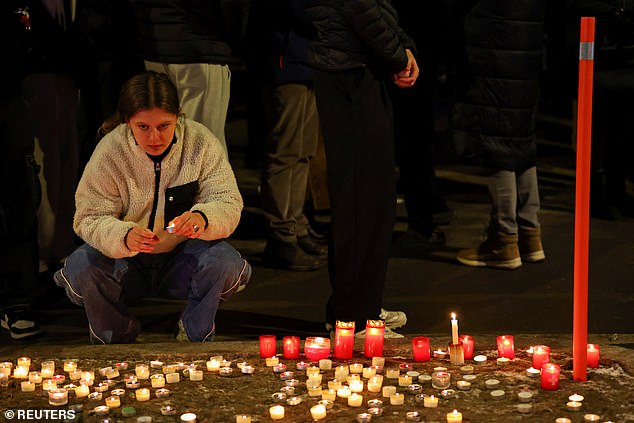 A woman holds a candle outside the "Le Constellation" bar, after a fire and explosion during a New Year's Eve party where several people died and others were injured, according to Swiss police, in the upscale ski resort of Crans-Montana in southwestern Switzerland, January 1, 2026
