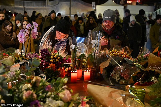 Mourners gather to leave flowers and candles at the scene after a fire broke out overnight at Le Constellation bar on January 1, 2026 in Crans-Montana, Switzerland