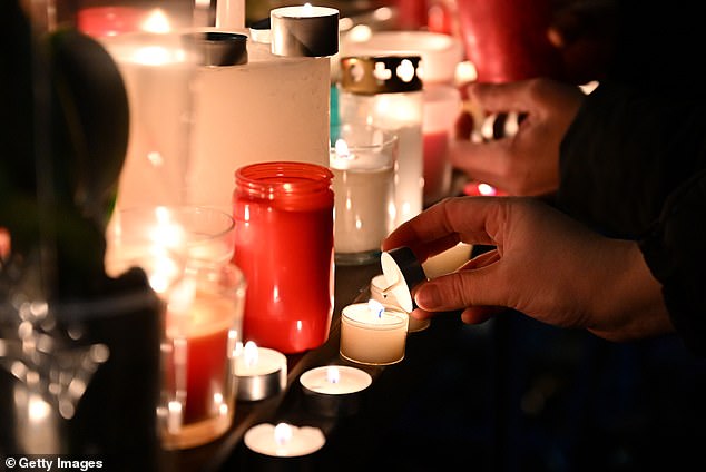 A mourner lights a candle after a fire broke out overnight at Le Constellation bar on January 1, 2026 in Crans-Montana, Switzerland