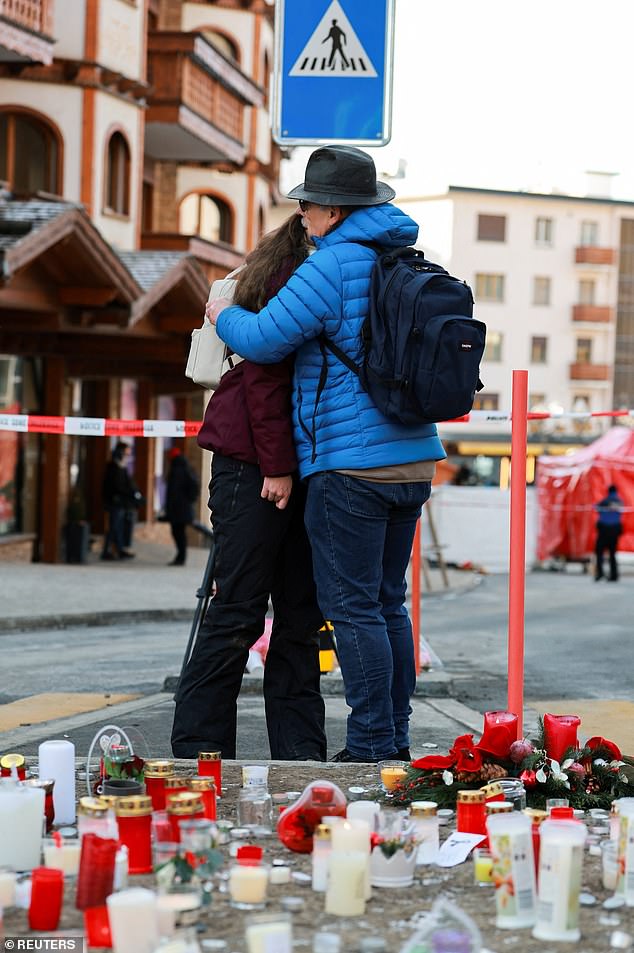 A man comforts a woman as they stand near candles placed for the victims as a tribute outside Le Constellation bar