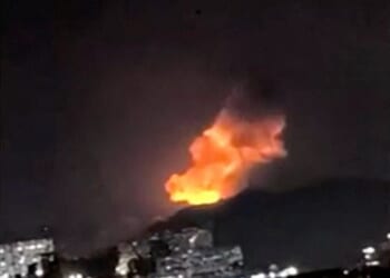 A column of smoke rises during multiple explosions in the early hours of the morning, in Caracas